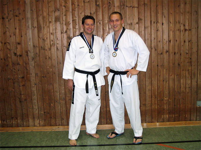 Trainer Adrian Bell und Christian Volk im Taekwondo-Anzug
          mit schwarzem Gürtel