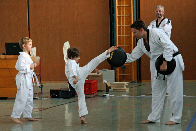 Training für
          Kinder, bei dem sie mit dem Fuß auf eine Bratze schlagen, die
          ein Trainer hält