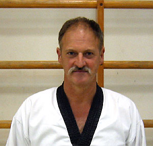 Taekwondo-Trainer
            Willi Hobel im weißen Trainingsanzug für Schwarzgurte mit
            schwarzem Kragen